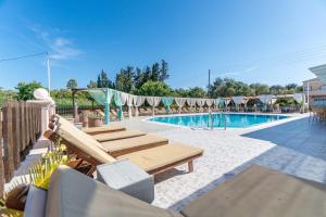 a swimming pool with chaise lounges next to a swimming pool at Saint Peter Bay Aparthotel in Kavos