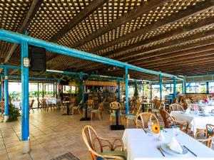 a restaurant with white tables and chairs and blue beams at Apartamentos BlueBay Beach Club in San Agustin