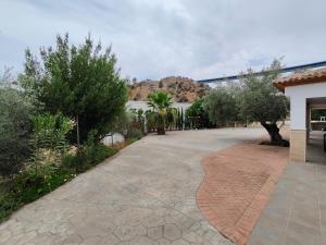 einen Backsteinsteg mit Bäumen und einem Berg im Hintergrund in der Unterkunft Casa rural Huertas del Castillo in Benamejí + 33 Fotos