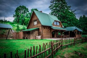 a wooden house with a green roof and a fence at Purvmaļi in Daugavpils