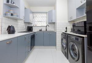 a kitchen with blue cabinets and a washer and dryer at 31 Madison Palms East in Johannesburg