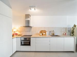 a kitchen with white cabinets and a sink at Maison Beaufort - uniek zicht op de jachthaven in Ostend +9 photos
