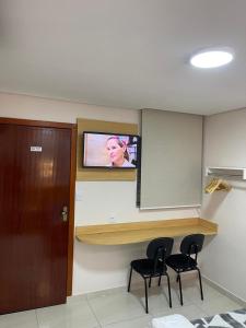 a room with two chairs and a tv on the wall at Hotel Flert - Tatuapé in São Paulo