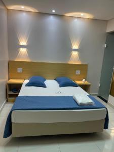 a bedroom with a large bed with blue pillows at Hotel Flert - Tatuapé in São Paulo