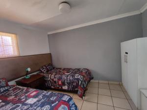 弗里尼欣Contractor Stay Vereeniging Guesthouse的一间卧室，有两张床、一张桌子和一扇窗户