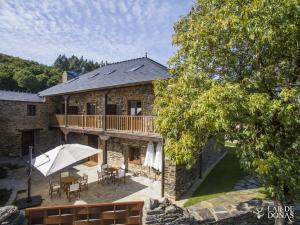 a stone house with a balcony and an umbrella at Lar de Donas in Meira