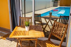a wooden table and chairs on a balcony with a pool at Wake up with the Sea Breeze- House with pool AP1 in Lavra