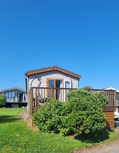 una pequeña casa con porche en el césped en 42 pine lodge & sea views, en Llanarmon