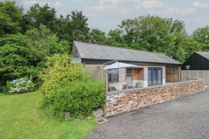 a house with a brick wall and a fence at The Stables in Saint Columb Major