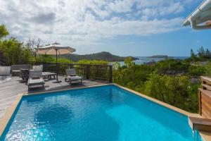 a swimming pool with chairs and an umbrella on a deck at Tropical Breeze Villa in Domaine du Levant in Petit Cul de Sac