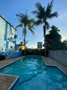 una piscina con palme e una casa di Pousada Canoeiros a Arraial d'Ajuda