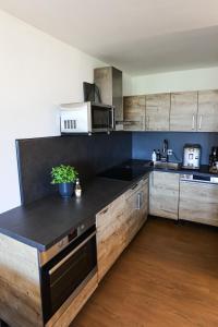 a kitchen with wooden cabinets and a black counter top at Sternenblick Lodge, im Harz, mit Schwimmbad und Sauna in Braunlage