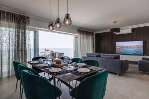 a dining room with a table and green chairs at 602 Sliema 3bed Seafront With Pool By Homely in Sliema