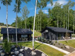 a black cottage with a garden and trees at Przystań Brzozowa Polana - Jezioro Mucharskie in Dąbrówka