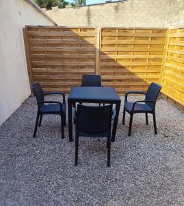 a table and four chairs with a table and a fence at Maison à 500 m du lac in Ardres