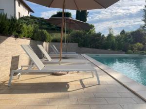2 sedie a sdraio e un ombrellone accanto alla piscina di Vigne dei Mastri a Costigliole dʼAsti