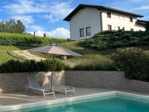 due sedie e un ombrellone accanto a una piscina di Vigne dei Mastri a Costigliole dʼAsti