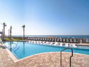 a swimming pool with lounge chairs and the beach at Phoenix West II #1407 in Orange Beach