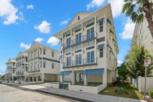 a tall white building on a street with palm trees at The Akoya & Pearl Houses at the Gemma - 2 Homes with Private Pools Just Steps to Clearwater Beach in Clearwater Beach