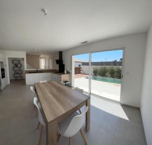 a kitchen and dining room with a wooden table and chairs at Villa moderne et confortable in Béziers