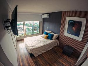 a small bedroom with a bed and a window at Santorini Apartamentos Amoblados in Pereira