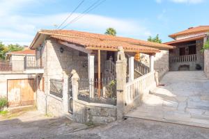 ein Steinhaus mit einem Tor und einem Zaun in der Unterkunft Casa Magariños in Gondomar