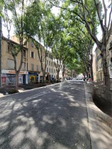 an empty street with trees on the sides of the road at Les Demeures de Castellane in Marseille