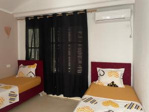two beds in a room with black curtains at Dar aissa in Aghīr