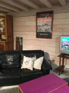 a black leather couch in a room with a television at La Grange in Saint-Père