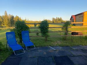 two blue chairs sitting in front of a fence at Žubites - 3 in Bērzgale