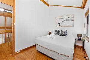 a white bedroom with a bed and a table at 11 Cottesloe - steps from beach - sleeps 3 in Perth +8 photos
