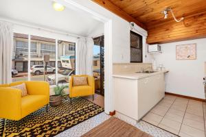 a kitchen and living room with two yellow chairs at 11 Cottesloe - steps from beach - sleeps 3 in Perth