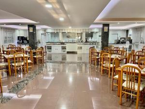 a dining room with tables and chairs and a kitchen at Hotel Nuevo Lanzada in A Lanzada