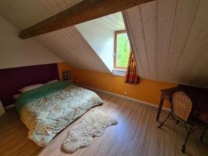 a bedroom with a bed and a desk and a window at La Grange in Saint-Père