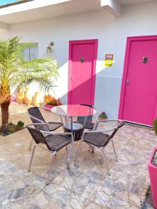 a patio with a glass table and chairs and pink doors at Bonita in Piranhas