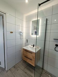 Un baño con lavabo y ducha de cristal. en Domki całoroczne Perełka Lubiatowska, en Lubiatowo