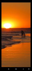 two people walking on the beach at sunset at Loft Necochea in Necochea