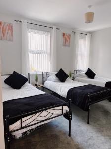 two beds in a room with two windows at Ty Noah- Newly Refurbished Home In The Heart Of Pembrokeshire in Milford Haven