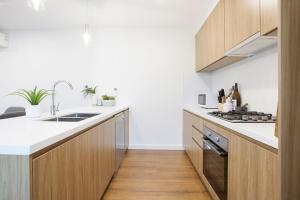 a kitchen with wooden cabinets and a sink at Stud Park Residence by Ready Set Stay in Rowville