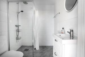 a white bathroom with a shower and a sink at Skärgårdslägenhet med havsutsikt i Sankt Anna! NR1 in Sankt Anna