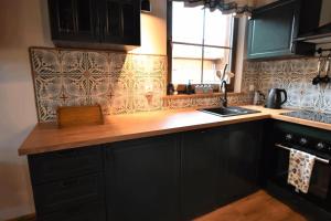 a kitchen with black cabinets and a wooden counter top at Domek na Kaszubach 7-1 - Ostoja Bukowo in Borowy Młyn