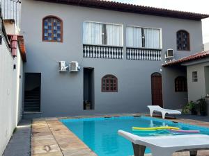 a house with a swimming pool in front of a house at Kitnet Aconchegante em ambiente Familiar a 100m Praia Camburi com Garagem in Vitória