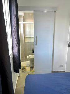 a room with a bathroom with a toilet and a door at Apartamento pé na areia praia Tombo in Guarujá