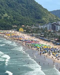 a group of people on a beach with umbrellas at Apartamento pé na areia praia Tombo in Guarujá