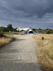 a dirt road with a building in the background at La Perle de l'Océan, à deux pas de la mer sans route à traverser, parking privé, piscine in Arzon