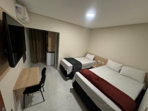 a hotel room with two beds and a desk and a television at Hotel Flex Tatuapé in São Paulo