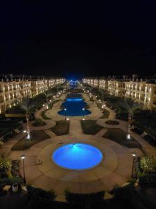 une grande cour avec deux grandes piscines la nuit dans l'établissement Laserina palme beach resort, à Ain Sokhna