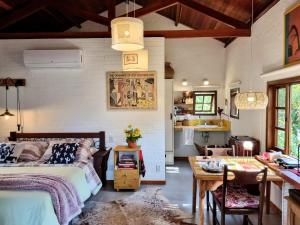 a bedroom with a bed and a table and a kitchen at Pousada Pinati in Teresópolis