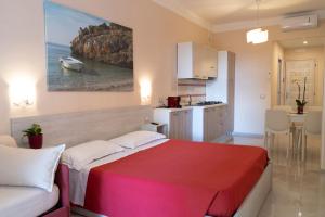 a bedroom with a red bed and a kitchen with a boat at Residence Cilento in Marina di Camerota