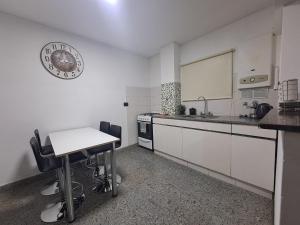 a kitchen with a table and a clock on the wall at Hornera Rodi - Lugar estratégico, cochera y pileta in Rosario
